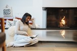 Woman sitting by the fireplace reading a book