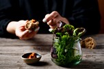 Salad in a glass, spread, behind it a person with a piece of bread