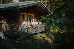 Couple in bathrobes in front of a wooden hut in the forest