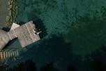 Person on a jetty surrounded by water from above
