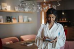 Woman in a bathrobe reads in a small notebook
