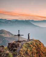 Man on a mountain peak surrounded by other peaks