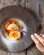 Apricot dumpling on a plate is cut up with a fork