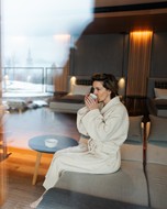 Woman in a bathrobe sits in the relaxation room and drinks tea