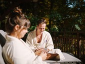 Two people in bathrobes lying in the sun on a terrace