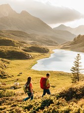 Hikers in a mountainous landscape with a lake and cows