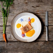 Gesund genießen mit feiner Bio-Küche Bio-Speise auf einem Holztisch, daneben eine Karotte