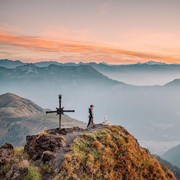 Man on a mountain peak surrounded by other peaks