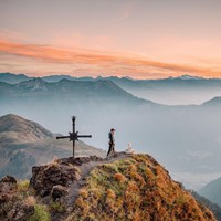 Man on a mountain peak surrounded by other peaks