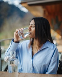 Woman sitting on a terrace and drinking spring water 
