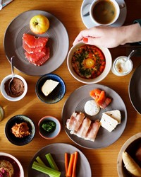Reich gedeckter Frühstückstisch mit Gemüse, Aufstrichen, Käse, Schinken und mehr