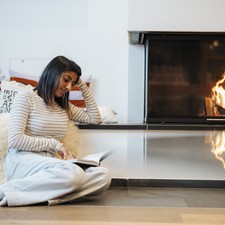 Woman sitting by the fireplace reading a book