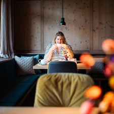 Eine Frau sitzt im Restaurant am Tisch und trinkt eine Tasse Tee.