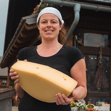 Cheesemaker holding a cut cheese wheel