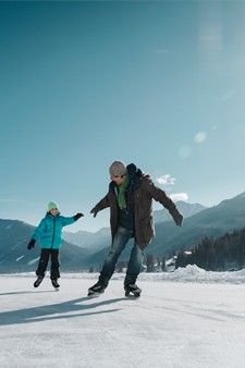 Man and child ice skating on the lake