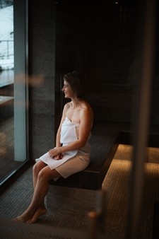 Frau sitzt in einer Sauna und schaut nach Draußen