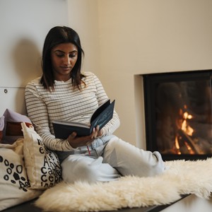 Woman sitting by the fireplace reading a book