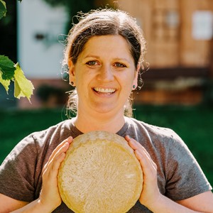 Cheesemaker holding a wheel of cheese