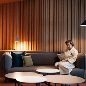 Woman in a bathrobe sits on a large couch and is immersed in a book