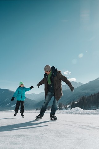 Man and child ice skating on the lake