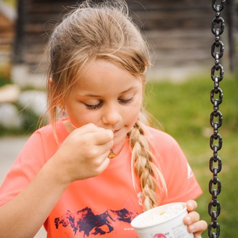Mädchen isst Eis aus dem Becher im Garten