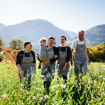 Familie Daberer in einer Blumenwiese, im Hintergrund die Berge