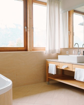 Enjoy the view of the valley and the mountains Washbasin, mirror and bathtub in bright bathroom with large windows