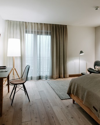 Hotel room with double bed, armchair, desk and large window