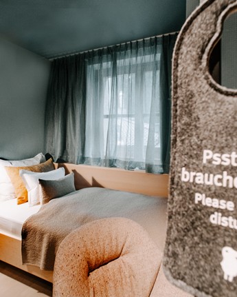 Bitte nicht stören Schild vor einem kleinen Hotelzimmer mit Einzelbett