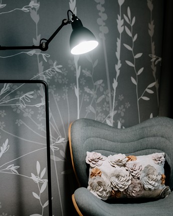 Armchair and lamp in front of grass wallpaper