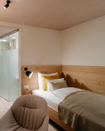 Cosy single room with French balcony Single bed, armchair and open wardrobe in the hotel room