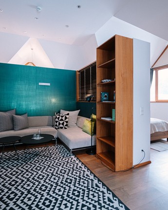 Sitzecke mit Sofa, Couchtisch, Teppich und Regal im Hotelzimmer