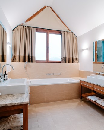 Badezimmer mit Badewanne und zwei gegenüberliegenden Waschbecken