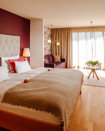 Großes Hotelzimmer mit Doppelbett, Sitzecke und Fensterfront