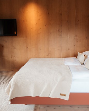 Wood-panelled hotel room with double bed, armchair and television.