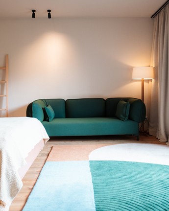 Your cosy room with a day sofa and small balcony Hotel room with green sofa and green accents in the carpet.