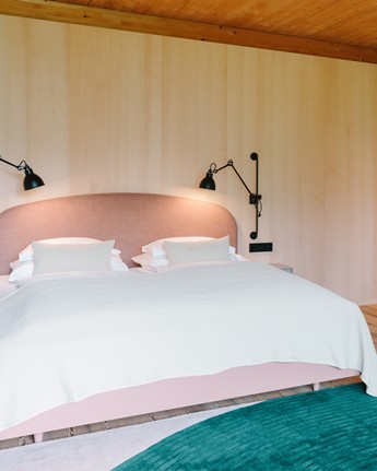 Enjoy your bright room with bold splashes of colour Hotel room with pink bed and dark green couch