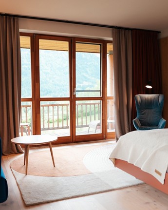 Wood-panelled hotel room with large windows facing the balcony.
