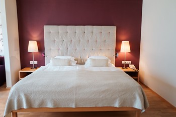 Double bed in a hotel room with a high, fabric-covered headboard.