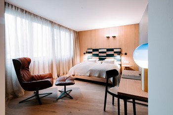 Hotel room with double bed, seating area and window front