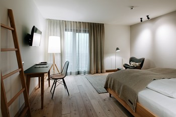 Hotel room with double bed, armchair, desk and large window