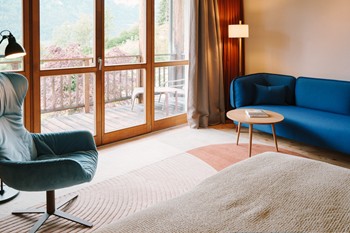 Sitting area in the hotel room with balcony and large panoramic window