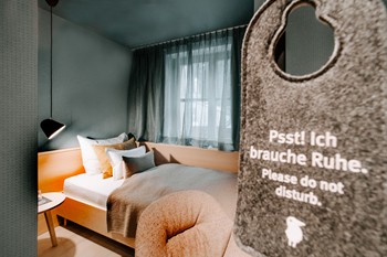 Do not disturb sign in front of a small hotel room with a single bed