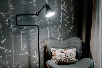 Armchair and lamp in front of grass wallpaper