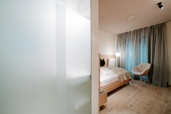 Hotel room with a view of the sleeping area and the glass door to the bathroom