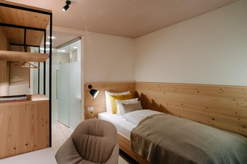 Single bed, armchair and open wardrobe in the hotel room