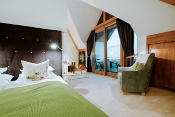 Double bed, armchair and large glass door to the balcony in the hotel room