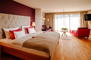 Large hotel room with double bed, seating area and window front