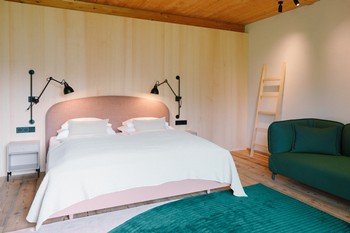 Hotel room with pink bed and dark green couch