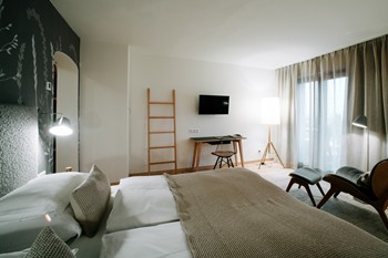 Hotel room with double bed, armchair, desk and large window